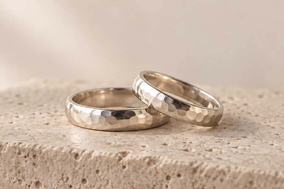 Two ring bands with a hand-hammered texture on a stone block.